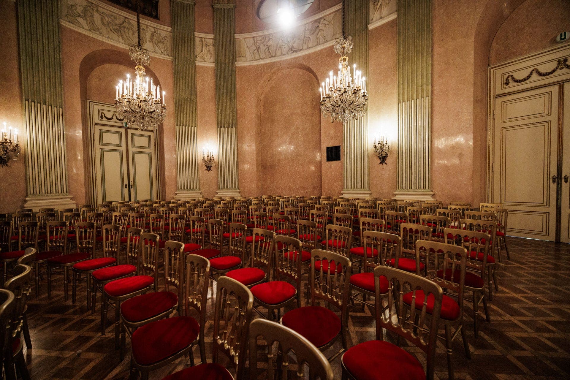 Empty concert hall with rows of gilded chairs and red cushions