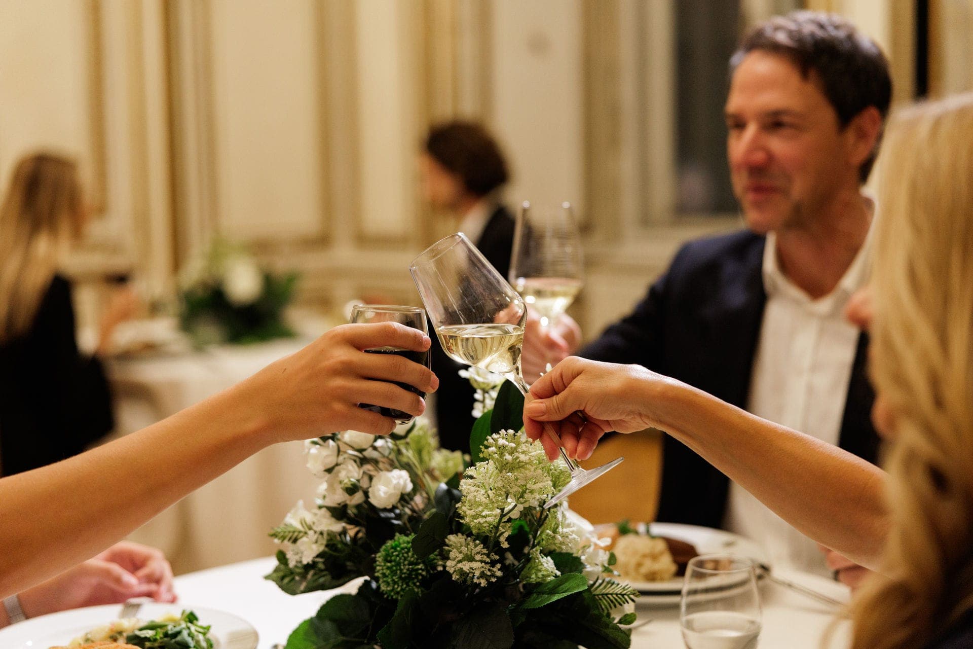 Guests toasting with wine at a dinner table with flowers