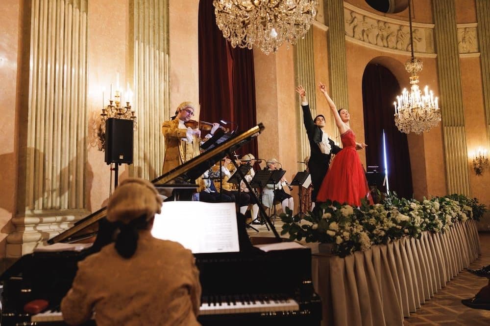 View past the pianist to the stage, where a ballet couple dances with the orchestra
