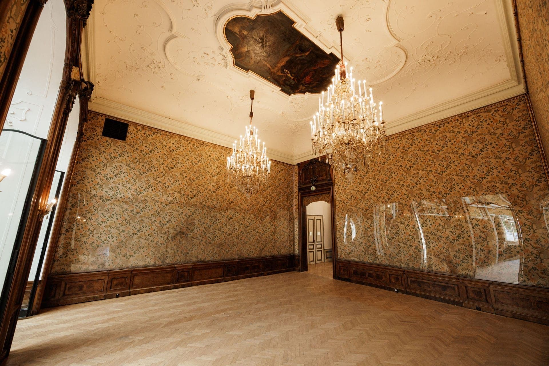 Hall with patterned silk walls, ceiling painting and two chandeliers