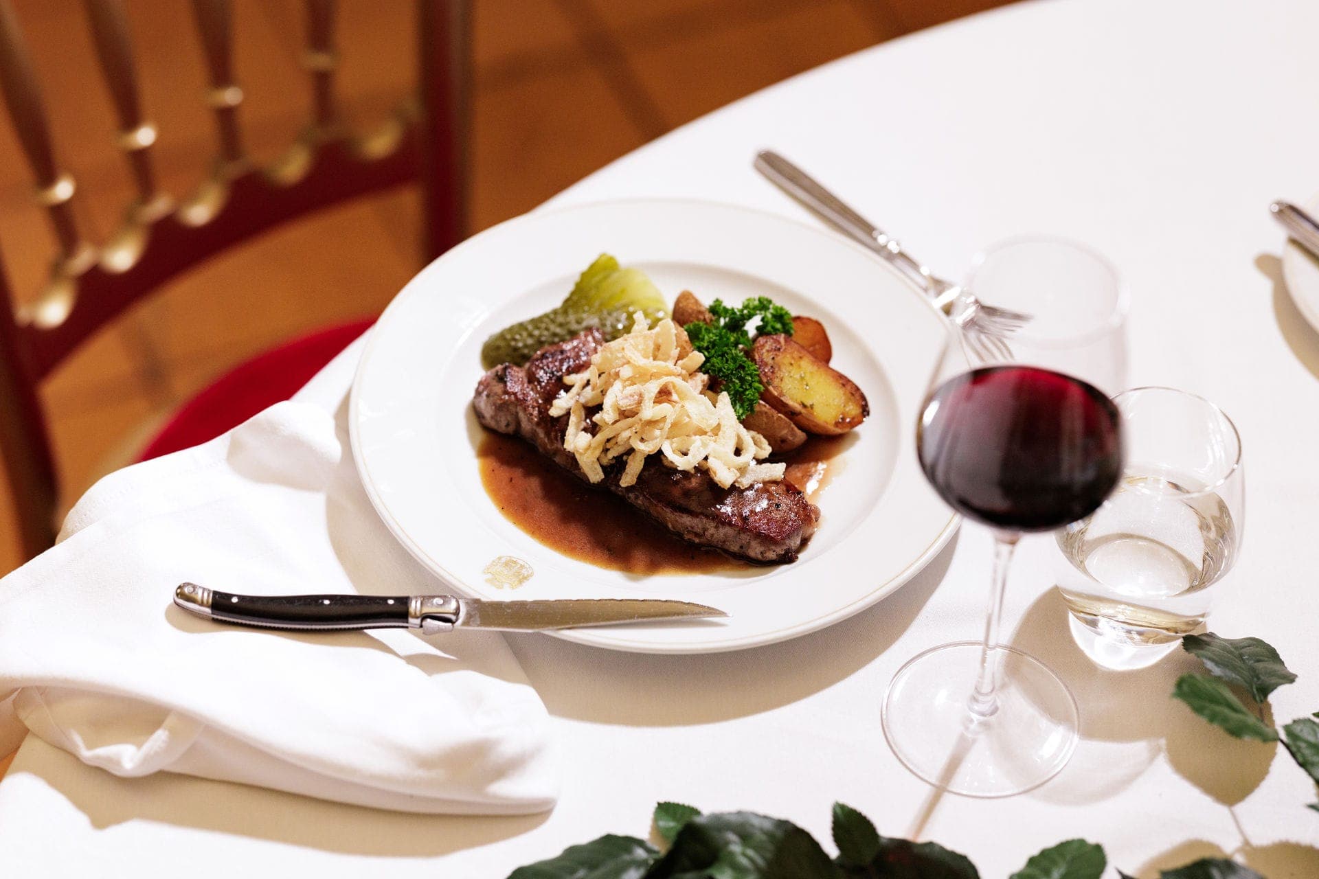 Steak with sauce, crispy onions and potatoes, with red wine
