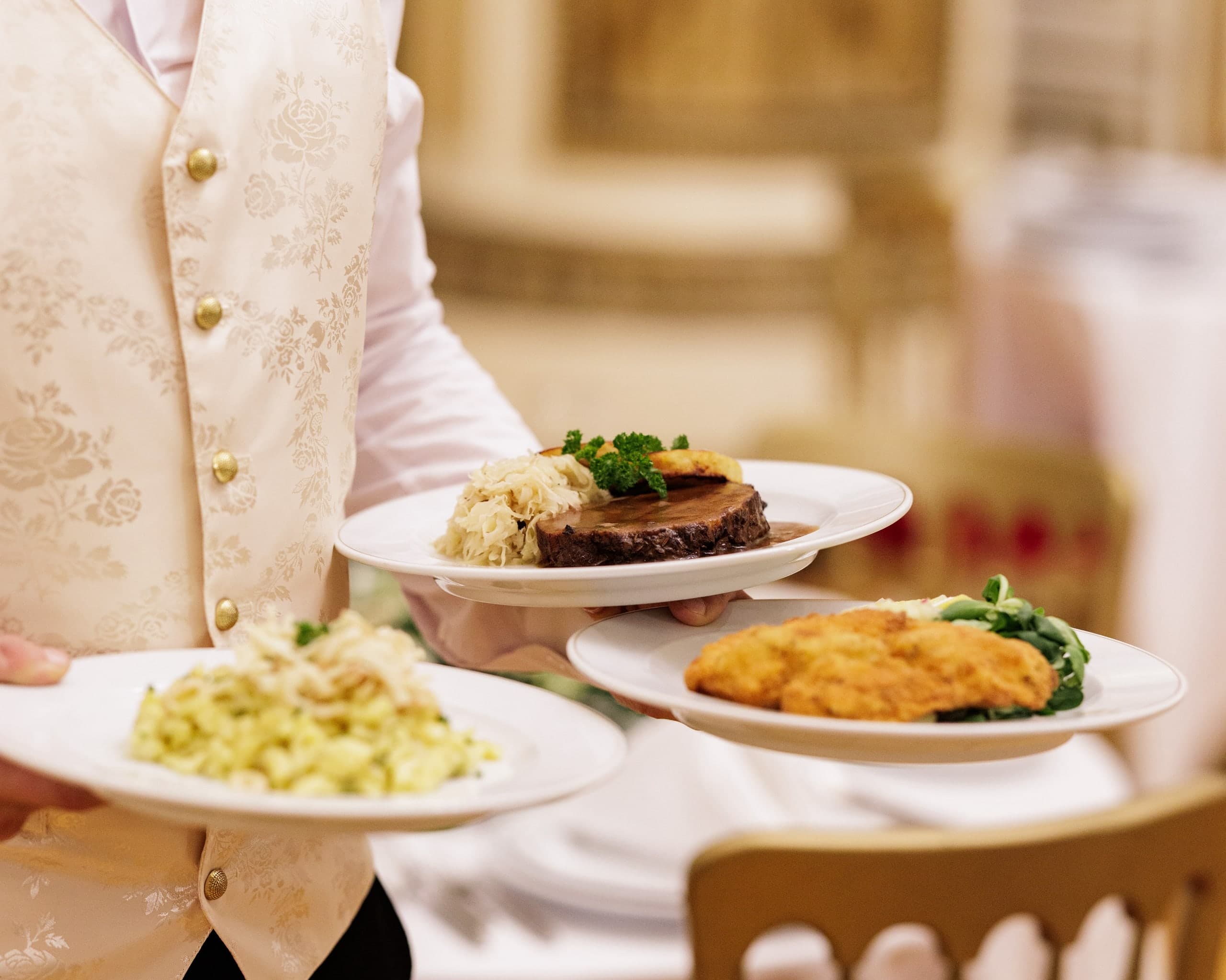 Waiter carrying plates of beef, schnitzel and pasta