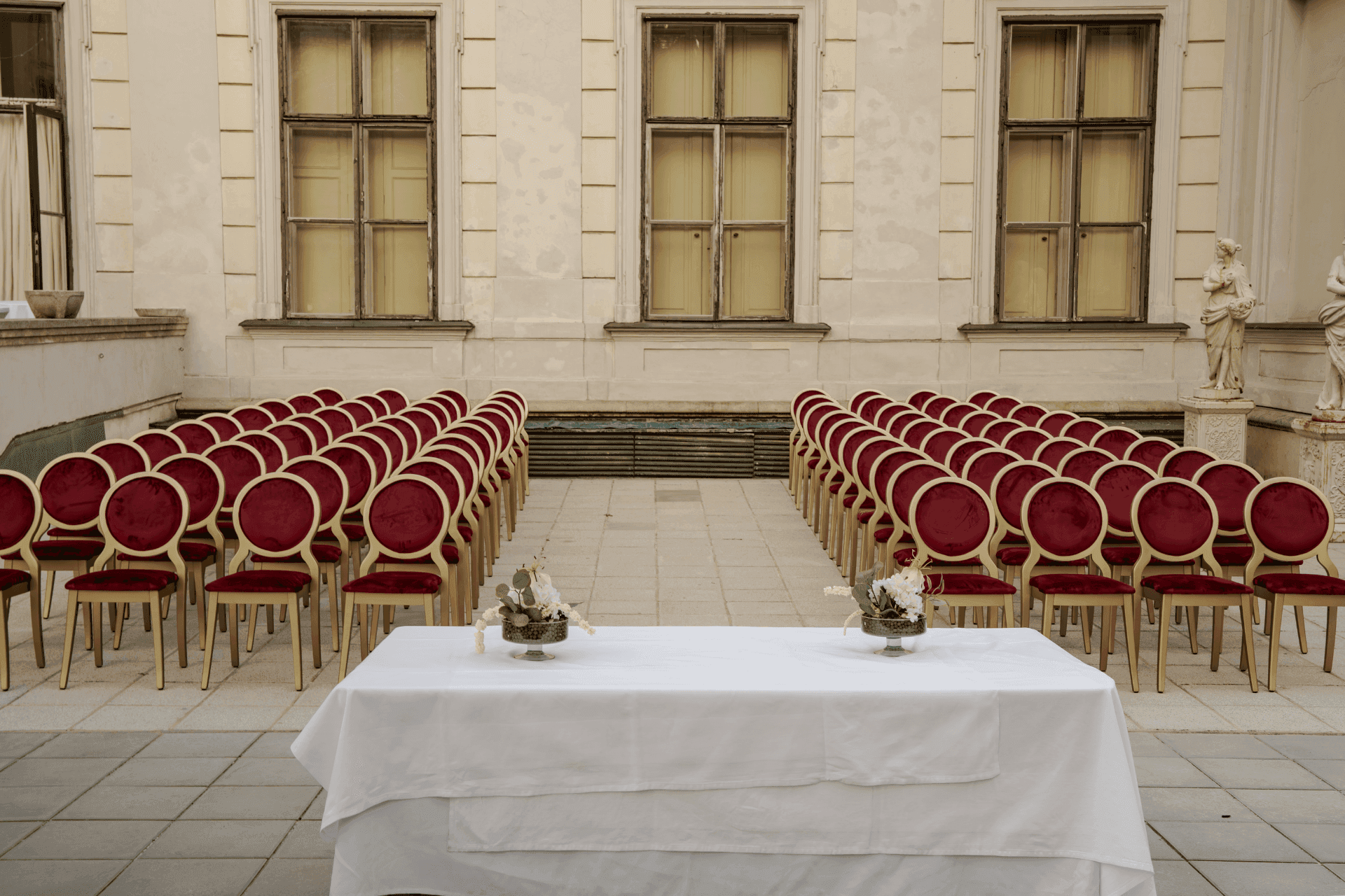 Courtyard terrace with rows of red chairs and a white table