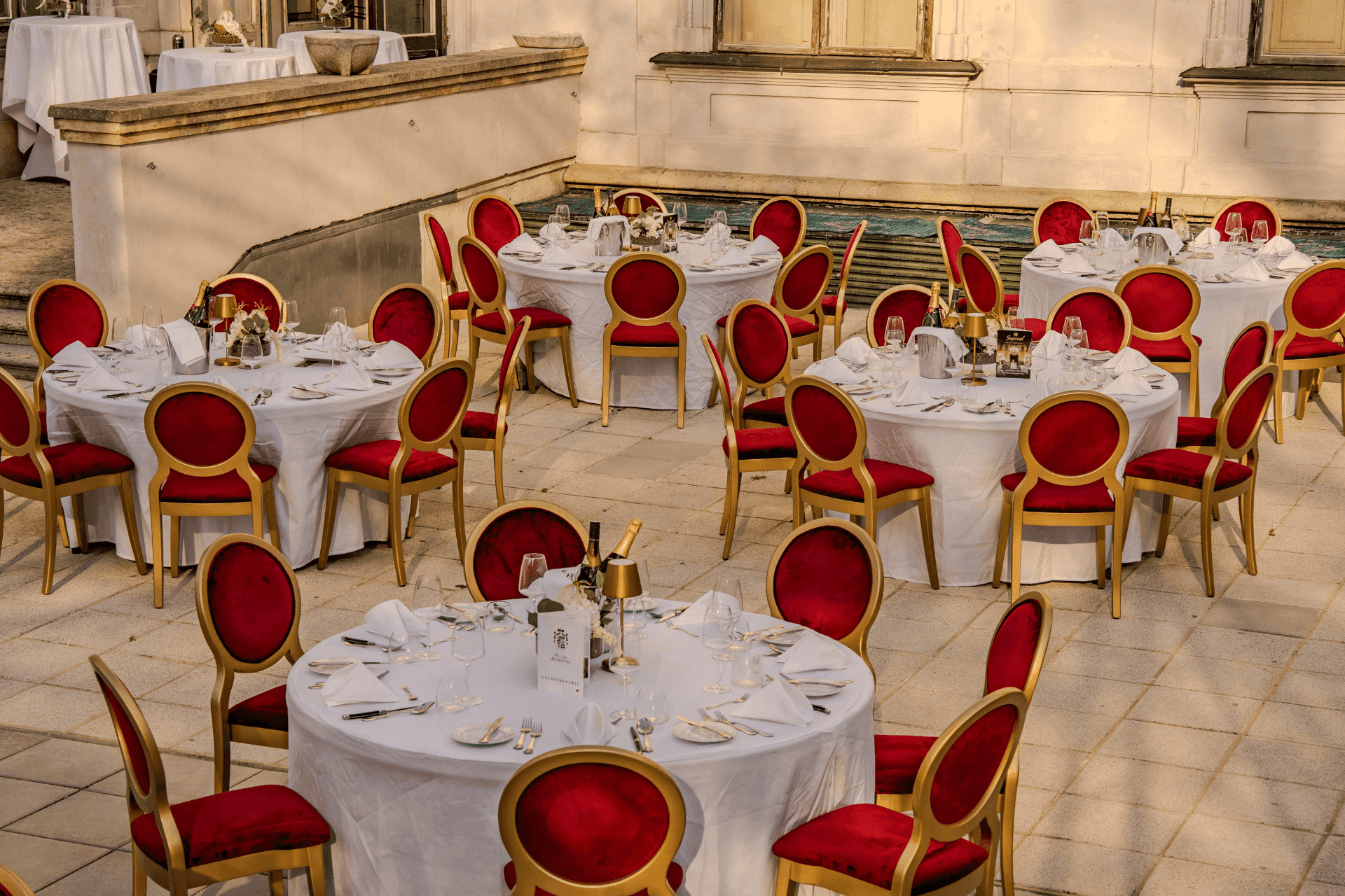 Set round tables with red velvet chairs on the courtyard terrace