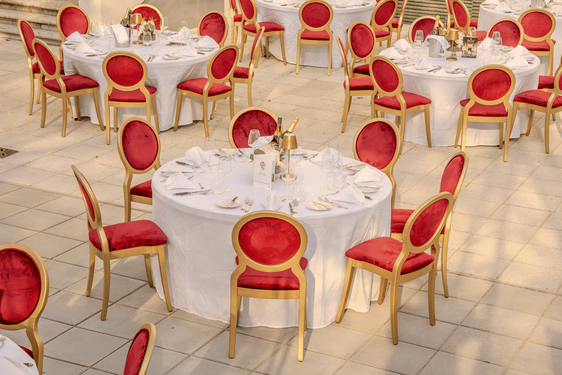 Set round tables with red velvet chairs on the courtyard terrace