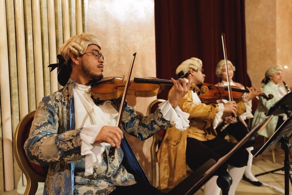 String players in powdered wigs and period costumes playing violins
