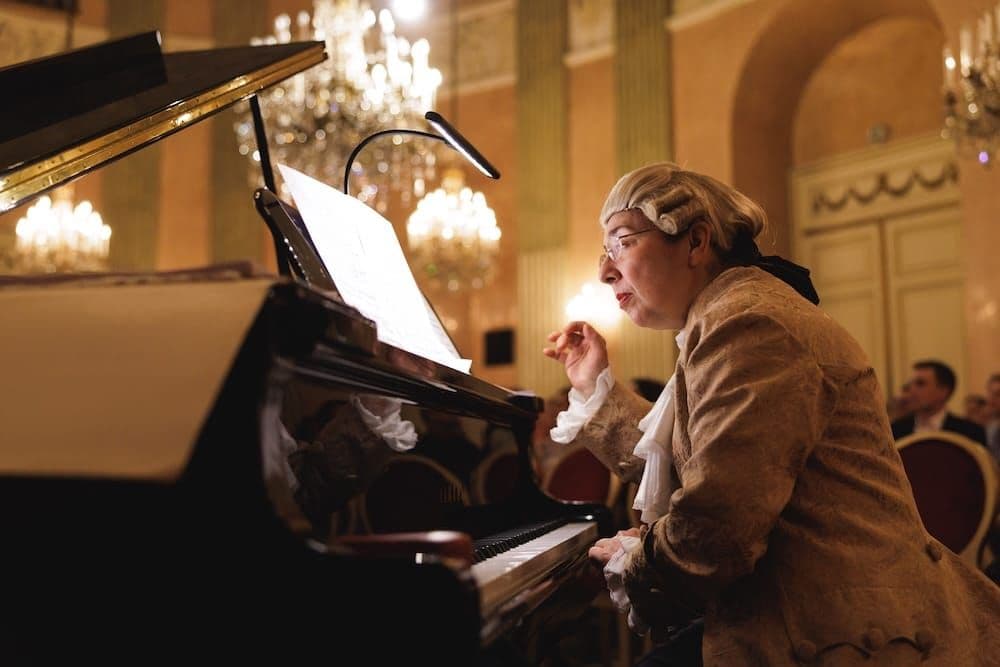 Pianist in period costume and wig at the grand piano under chandeliers