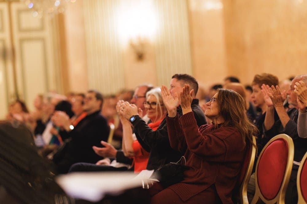 Audience on red chairs applauding enthusiastically