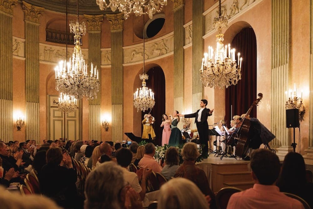Tenor with arms outstretched, singers and orchestra before a full hall